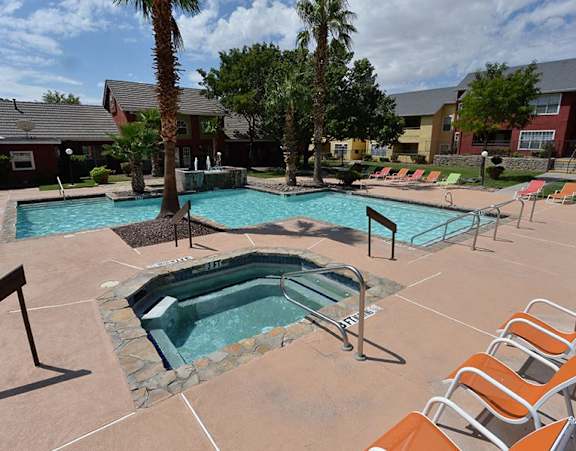 A pool area with a hot tub and lounge chairs.