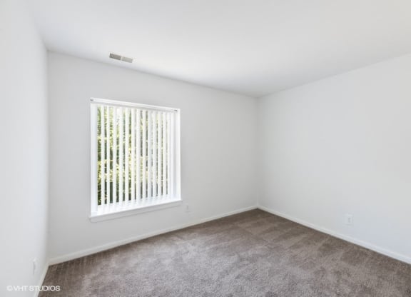 an empty room with a window and carpet