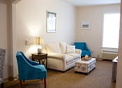 Thumbnail 2 of 6 - a living room with a white couch and two blue chairs