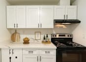 Thumbnail 8 of 8 - A kitchen with white cabinets and a black stove top oven.