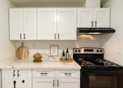 Thumbnail 8 of 8 - A kitchen with white cabinets and a black stove top oven.