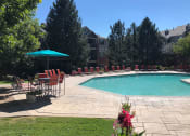 Thumbnail 39 of 40 - Westlake Greens Pool with orange lounge chairs, turquoise umbrella and grassy area