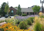 Thumbnail 36 of 40 - Westlake Greens Leasing Office brick front entrance with yellow flowers and plants in from