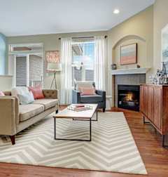 A living room with a fireplace and a striped rug.