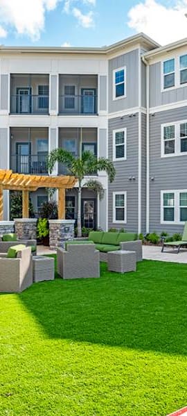 an outdoor lounge area with a grassy area and a large building in the background