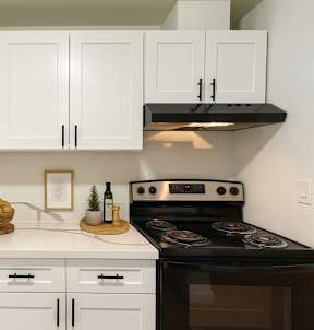 A kitchen with white cabinets and a black stove top oven.