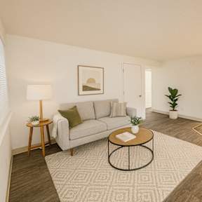 A living room with a grey couch, a coffee table, and a dining table with chairs.