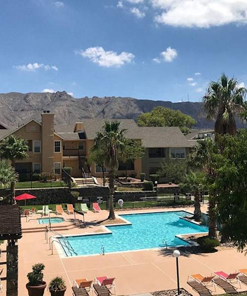 A pool surrounded by chairs and mountains in the background.