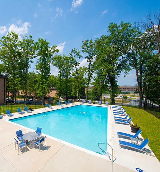 a swimming pool with blue and white chairs and a building in the background