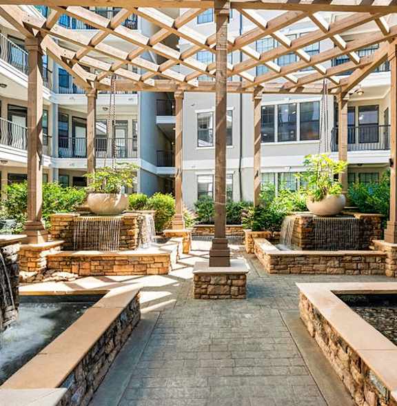 A courtyard with a fountain and a wooden pergola.