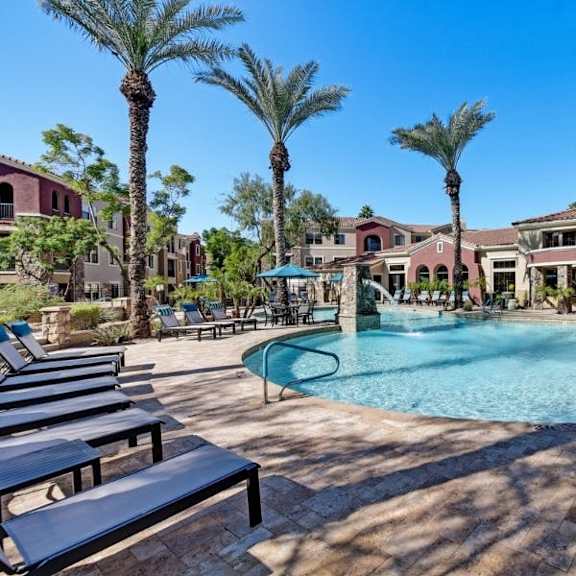 The outdoor pool with pool chairs, tables, and chairs at Desert Club. 
