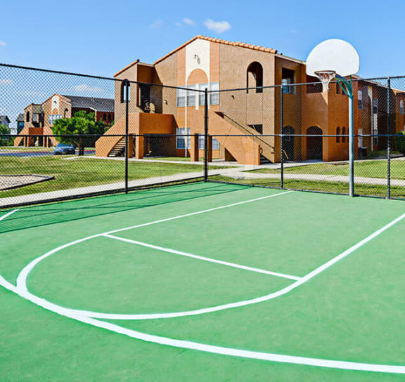 a green basketball court in front of a brick building