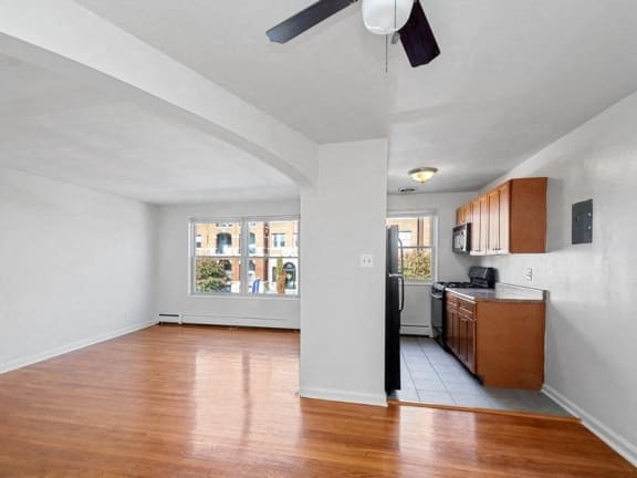 an empty living room and kitchen with wood floors and a window