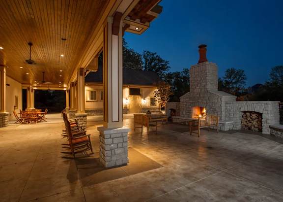 A patio with a fireplace and chairs is lit up at night.
