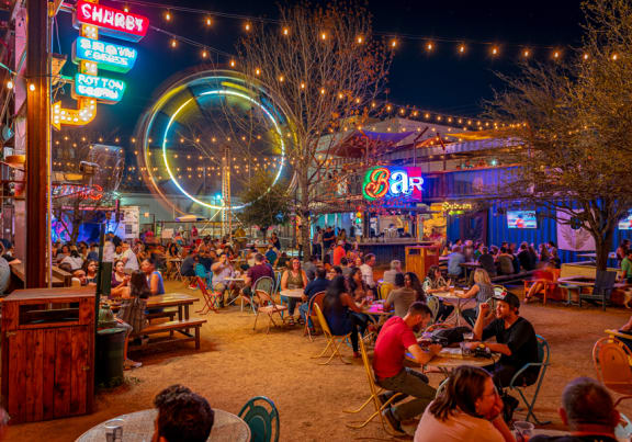 a crowd of people sitting at tables in an outdoor restaurant at night