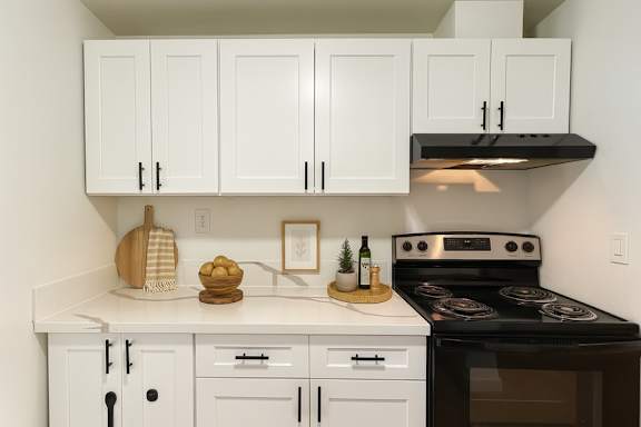 A kitchen with white cabinets and a black stove top oven.
