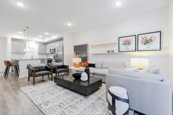 A modern living room with a grey sofa, a coffee table, and a dining table with chairs.