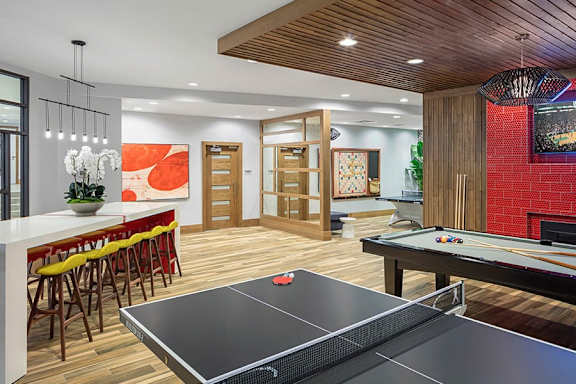 A ping pong table is in the middle of a room with a bar and a television.