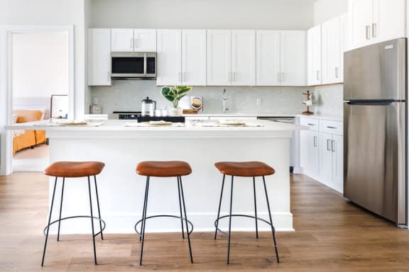 a white kitchen with three stools in front of a counter