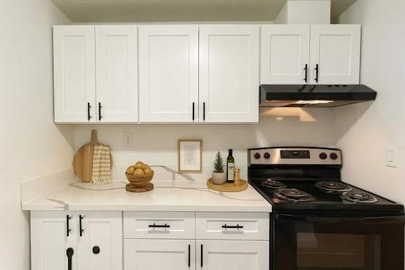 A kitchen with white cabinets and a black stove top oven.