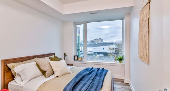 a bedroom with a large window and a bed with a blue blanket