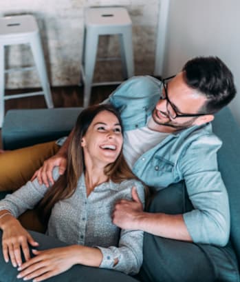 a man and woman sitting on a couch laughing