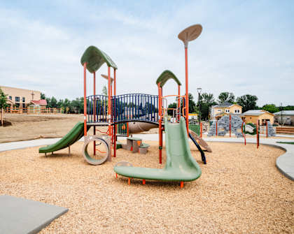 A playground with a green slide and a red and white slide.