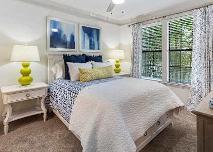 A bedroom with a bed, two lamps, and a painting on the wall.