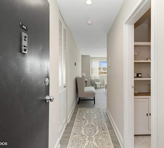 a hallway with a black door and a couch and chair in the background