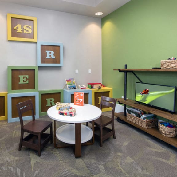 a play room with a table and chairs and alphabet letters on the wall at The Reserve at 4S Ranch, California