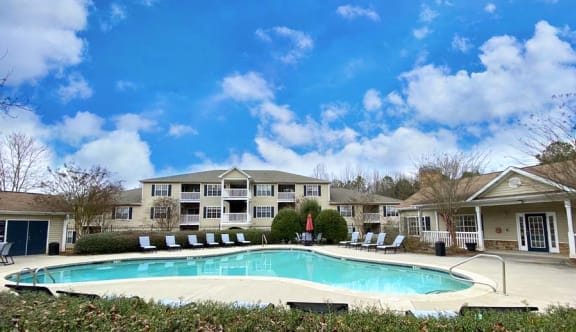 a swimming pool with chairs around it in front of a building