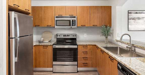 A modern kitchen with wooden cabinets and stainless steel appliances.