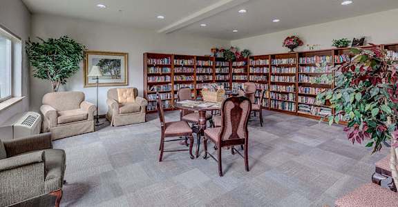 A room with a grey carpet and a bookshelf filled with books  at VINTAGE AT BURIEN, Burien, WA