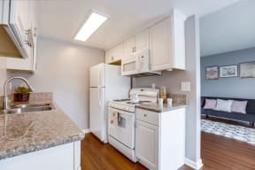Apartments for Rent in West Covina - Tuscany Villas Kitchen with White Custom Cabinetry, Hardwood Flooring, White Appliances, and Grey Walls
