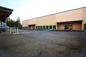 A large warehouse building with a parking lot in front.