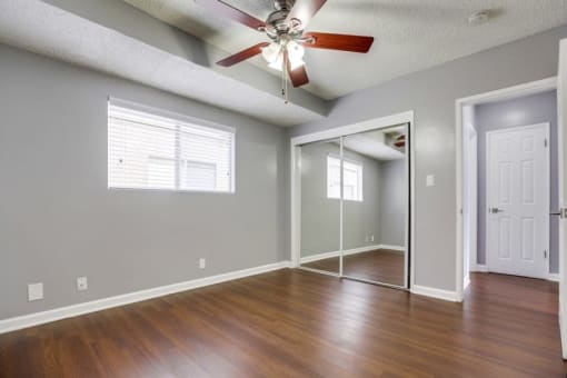 Pet-Friendly Apartments in West Covina CA - Tuscany Villas - Bedroom with Wood-Style Flooring, Mirrored Closet Door, and a Ceiling Fan
