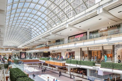 a shopping mall with glass ceilings and people walking