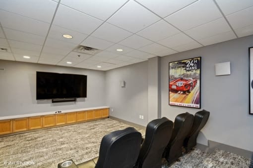 a small conference room with a flat screen tv and leather chairs