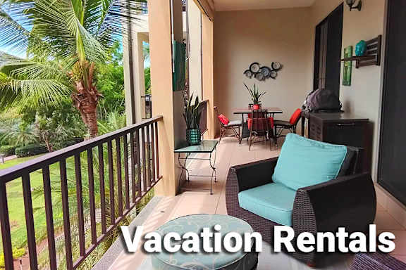 A balcony with a chair and a table overlooking a palm tree.