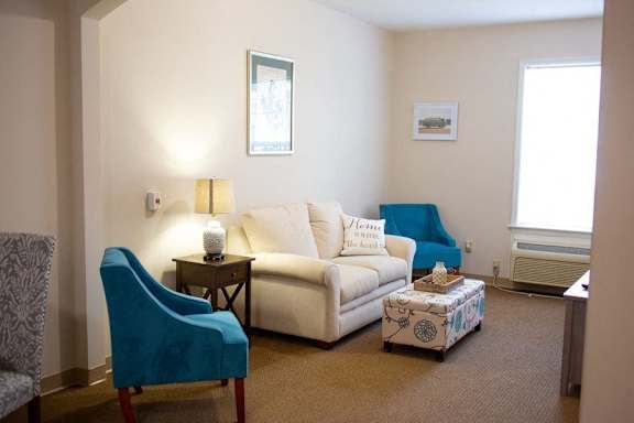 a living room with a white couch and two blue chairs