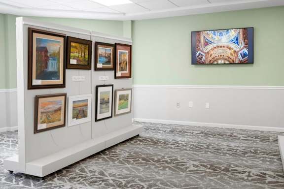 A wall of framed artwork is on display in a room.