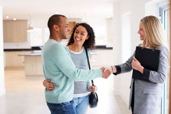 a man shaking hands with two women in an empty house