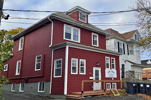 A blue and white building with a red car parked in front.