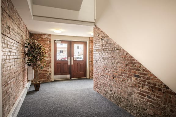 A hallway with a brick wall on one side and a carpeted floor.