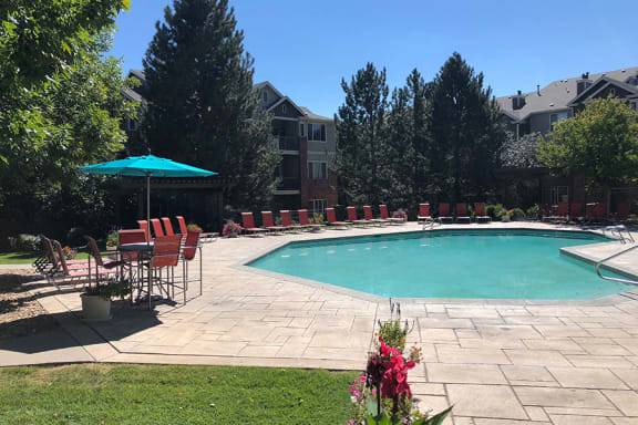 Westlake Greens Pool with orange lounge chairs, turquoise umbrella and grassy area