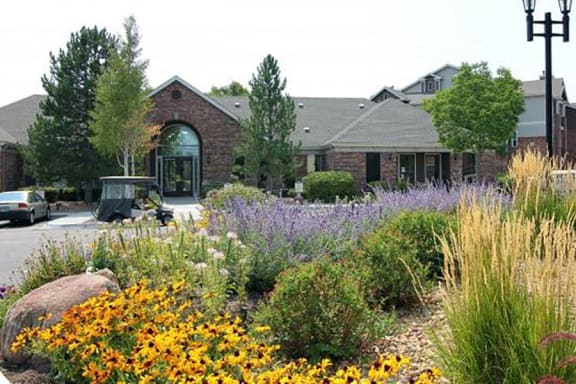 Westlake Greens Leasing Office brick front entrance with yellow flowers and plants in from