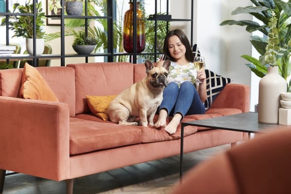 a woman sitting on a couch with a dog and a glass of wine