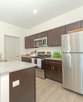 a kitchen with stainless steel appliances and a granite counter top at Midtown Sam Houston Apartments, Huntsville, TX, 77340