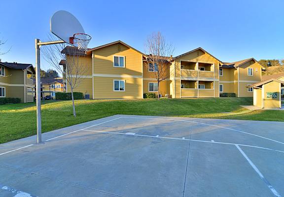 A basketball court is located in front of apartment buildings.