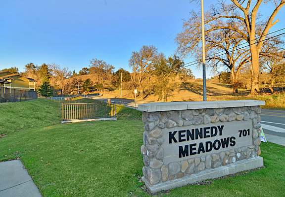 A stone sign that says Kennedy Meadows stands in a grassy area.